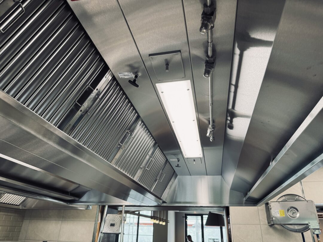 Abb.: Moderne Küchenhaube mit Sensoren vor und hinter der Beleuchtung, mit Zuluftführung
(Induktionsluft) und integrierter Feuerlöschanlage rechts neben der Beleuchtung